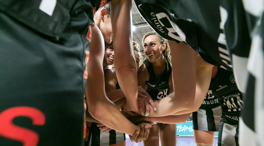 Collingwood Magpies huddle with Geva Mentors face at the centre smiling